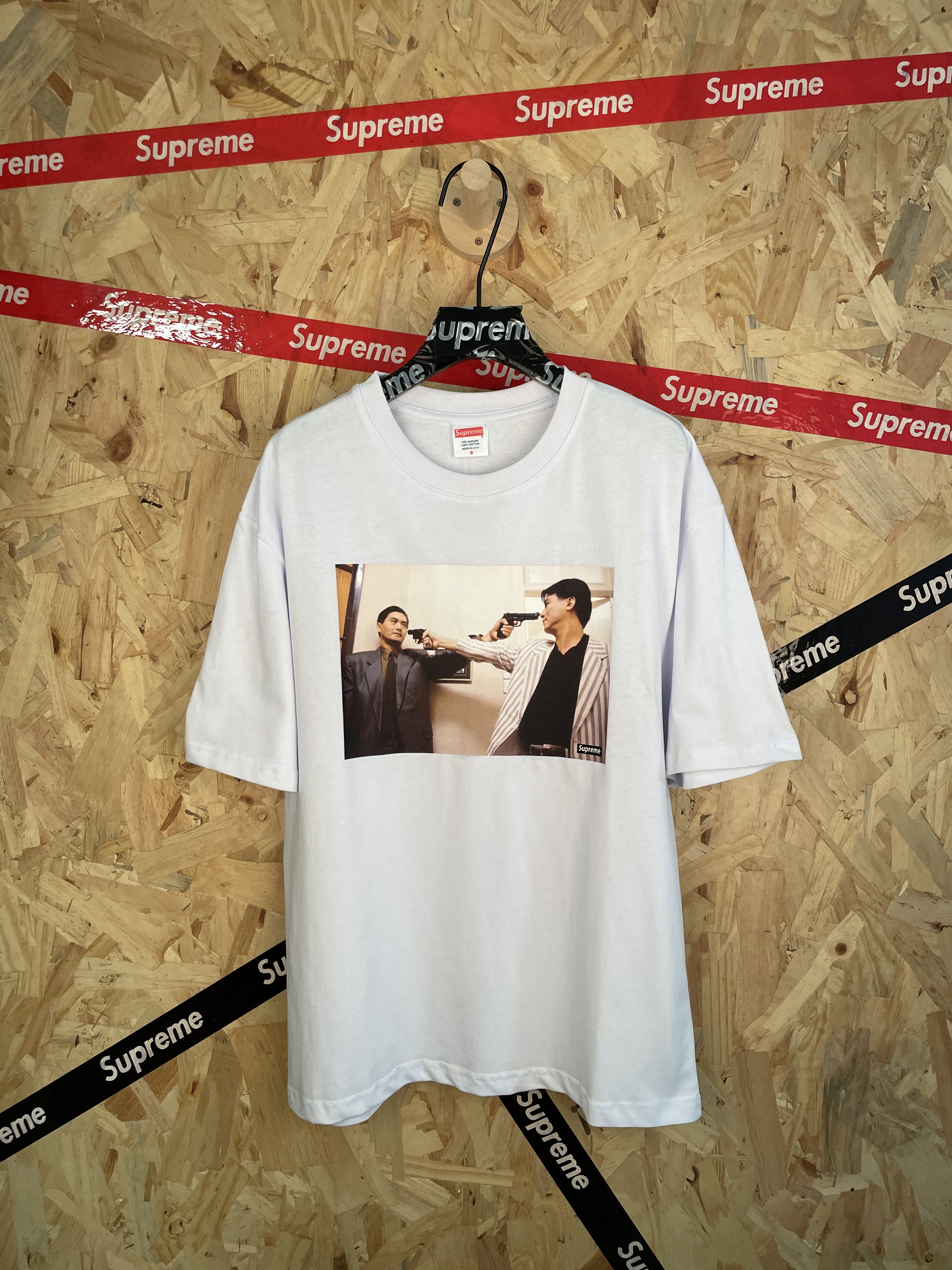 White short-sleeved T-shirt with a movie scene print featuring a raised double-gun design on the bottom