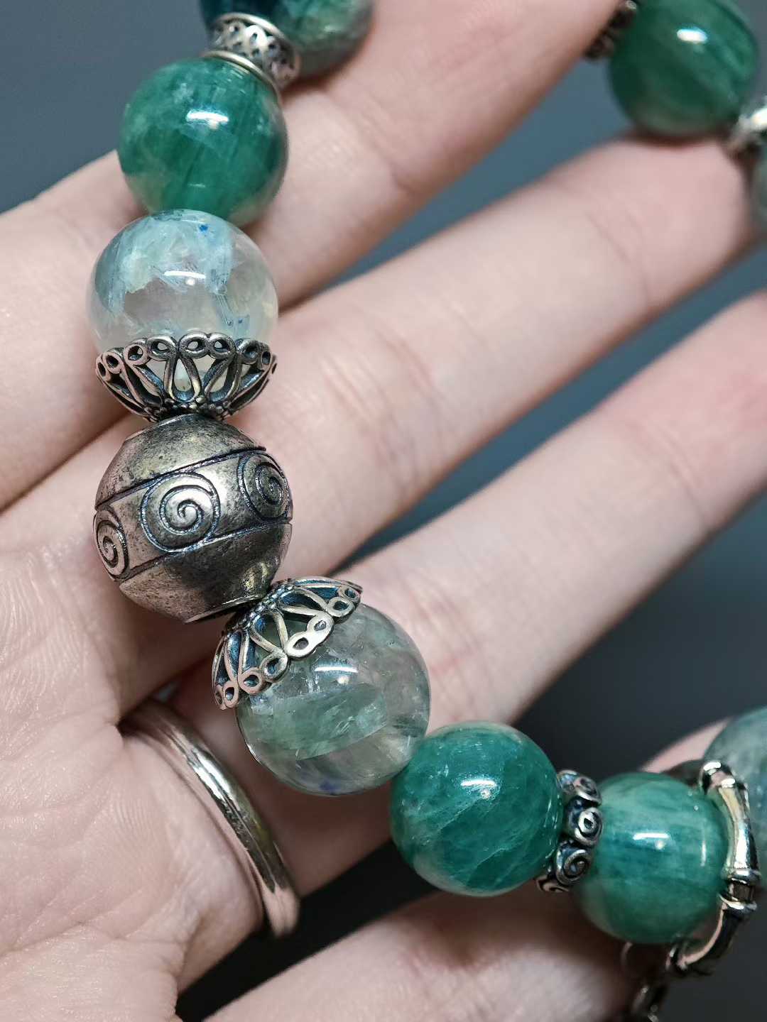 Turquoise waves rock green reflections,White egrets skim the cool shallows.Distant peaks hold misty verdure,A light boat drifts into the painted scene.